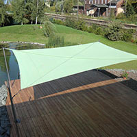 Grünes Sonnensegel über einer Terrasse an einem Teich